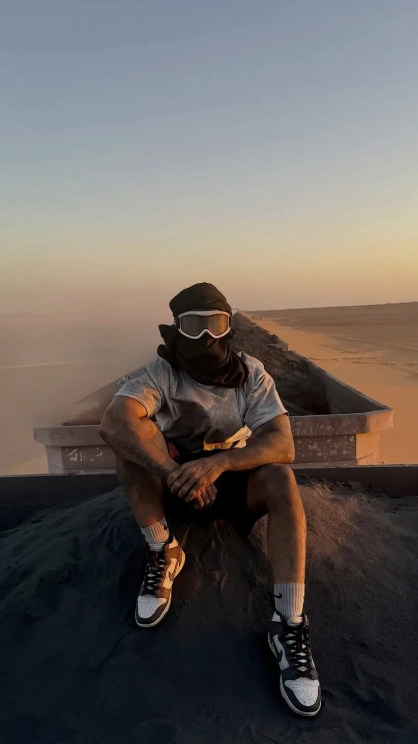 Noureddine sitzt bei Sonnenuntergang auf einer Mauer
